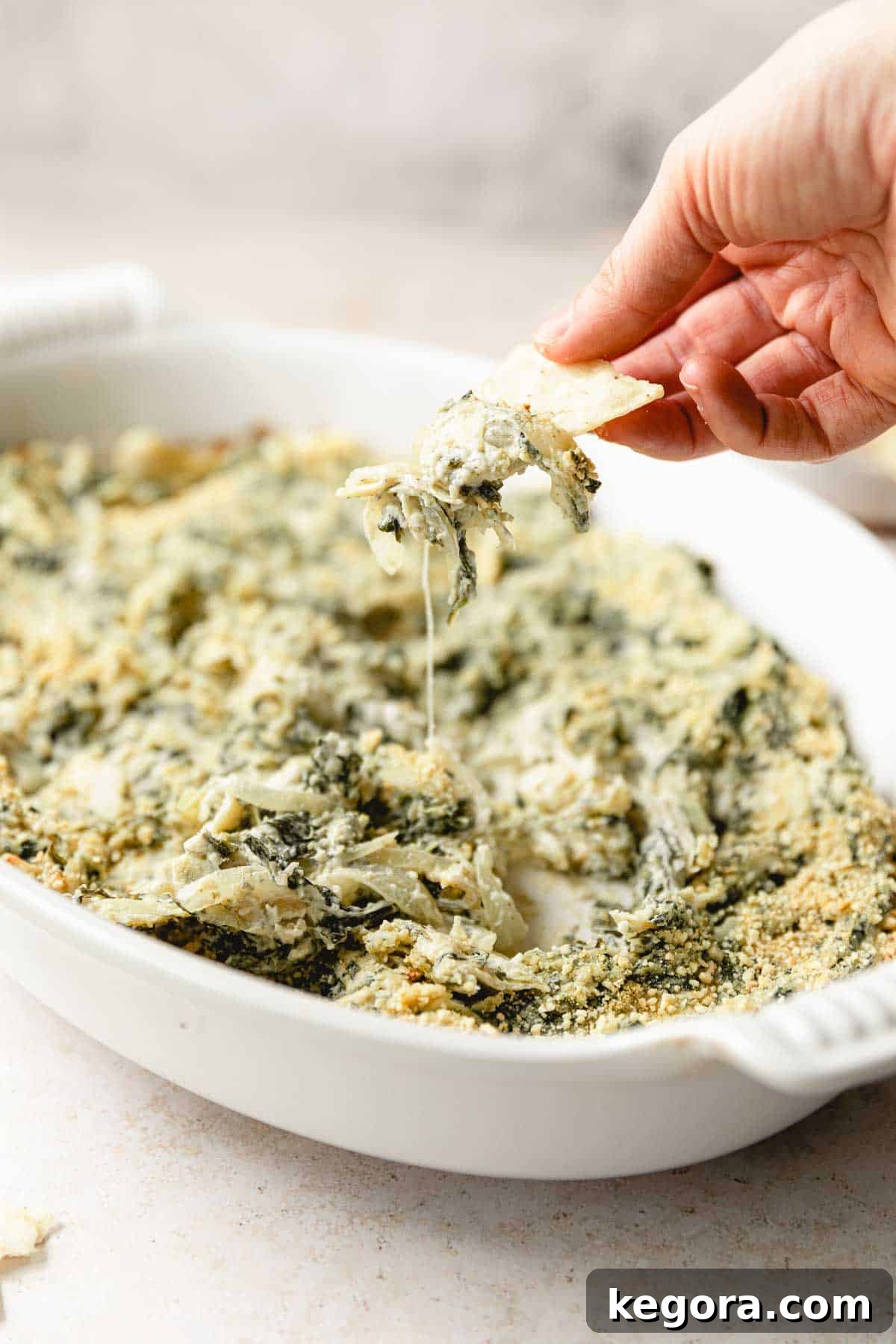 Creamy Spinach Artichoke Dip Without Dairy 2 spinach artichoke dip in baking dish with chip for dipping