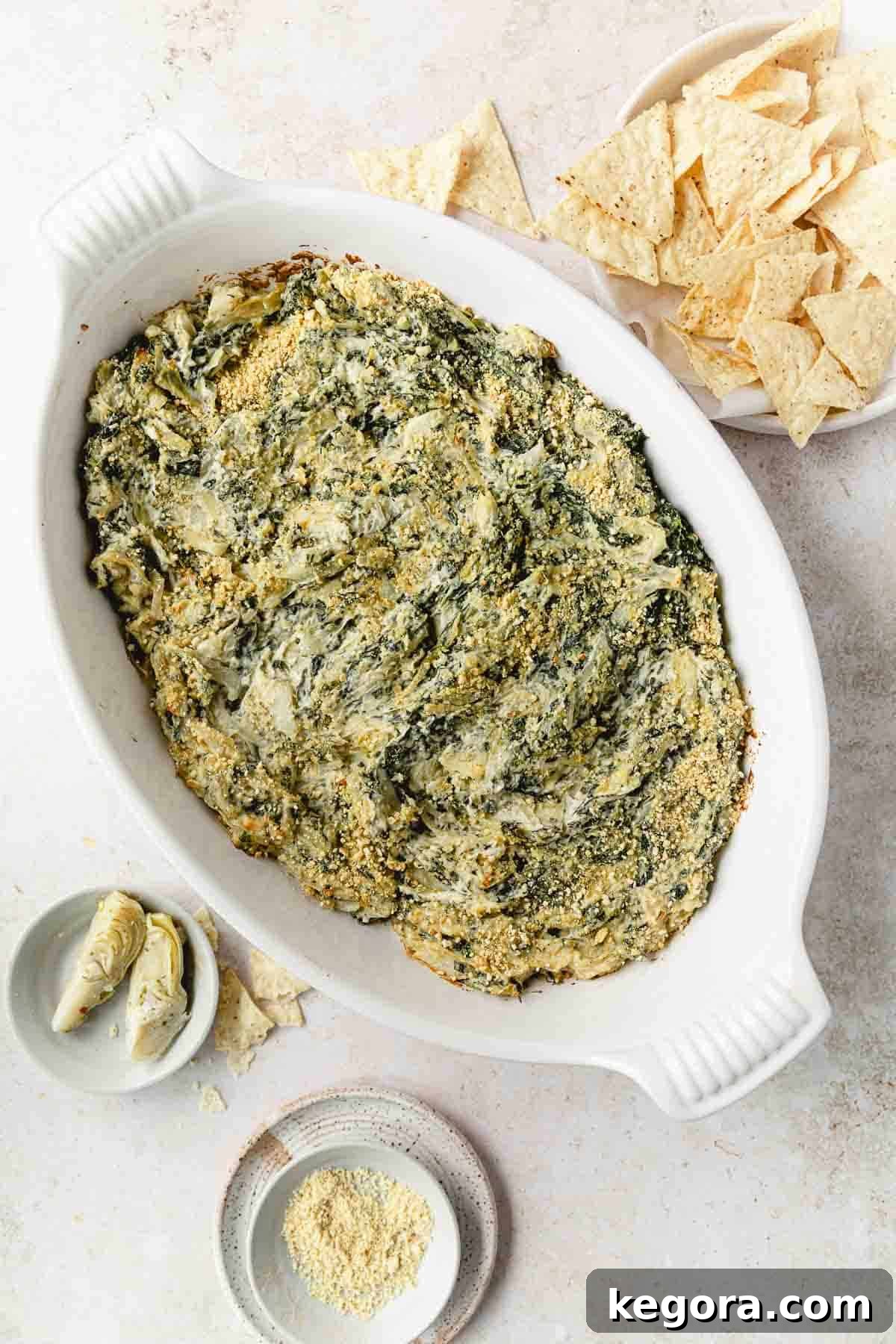 Creamy Spinach Artichoke Dip Without Dairy 8 overhead shot of baked artichoke dip with chips on white background