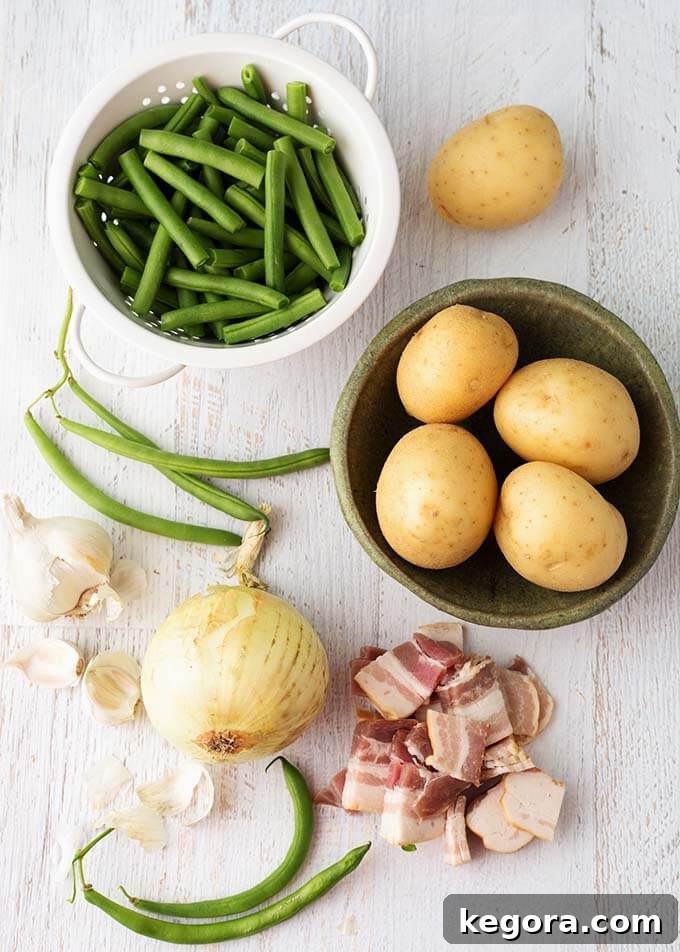Fresh ingredients for making Instant Pot Green Beans with New Potatoes and Bacon, including green beans, new potatoes, bacon, and onion, arranged on a white wooden background.