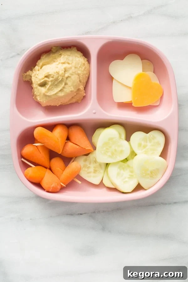 Pink plate with heart shaped vegetables and hummus for a healthy Valentine's snack