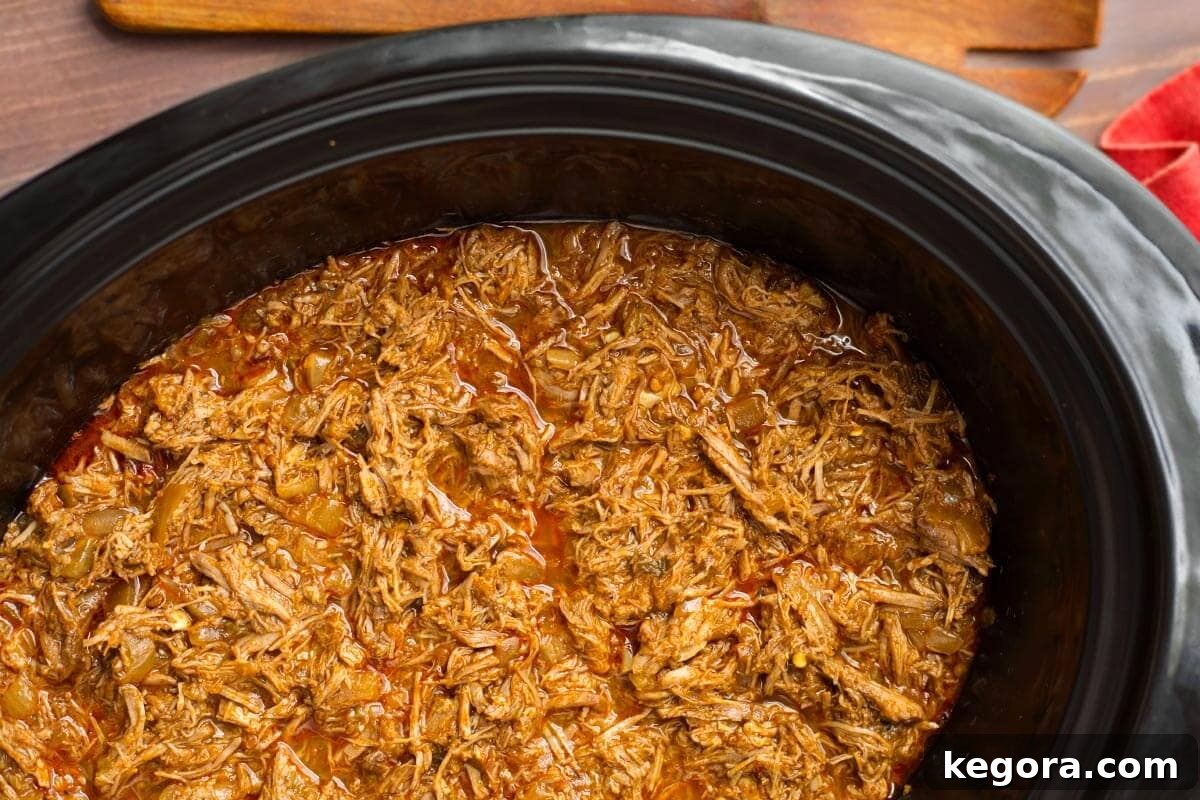 Slow Cooker Barbacoa shredded beef, rich in color and texture, resting tenderly in the crockpot, ready to be served.