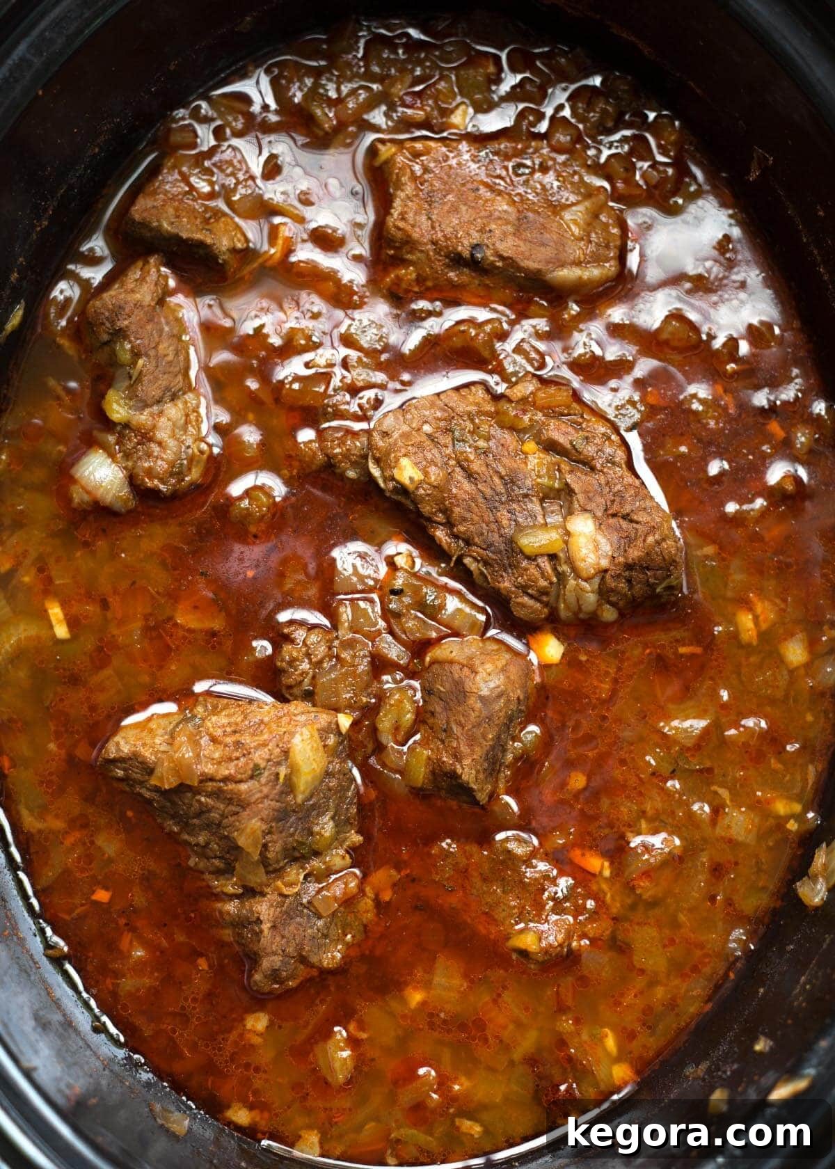 Top view of Slow Cooker Barbacoa Beef, rich and inviting, simmering gently in a black slow cooker, ready to be dished out.