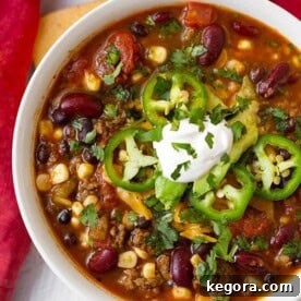 Taco Soup topped with sliced jalapenos and sour cream in a white bowl