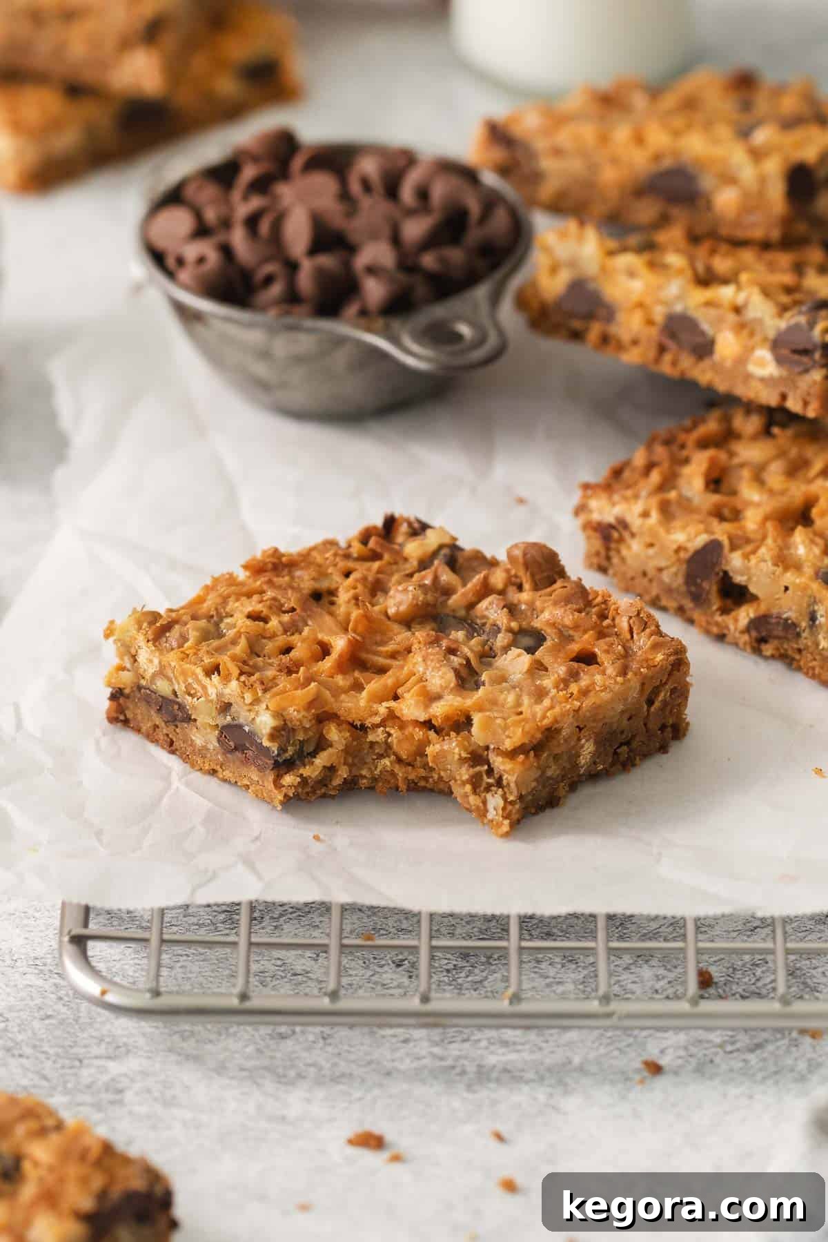Gluten-Free Magic Bars 11 A close-up of a gluten-free 7-layer bar with a bite taken out, resting on a cooling rack, highlighting its gooey texture.