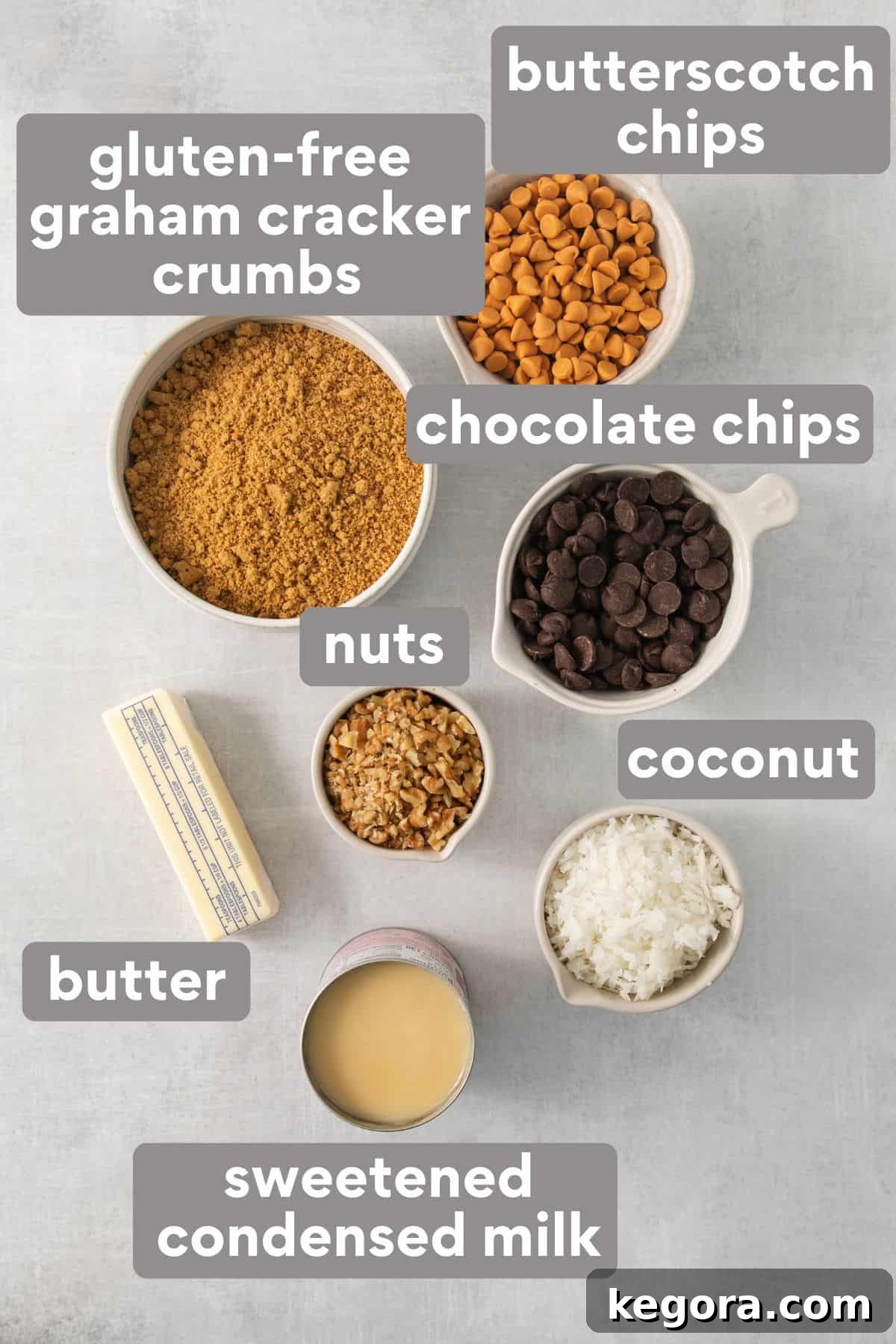 Gluten-Free Magic Bars 3 A selection of ingredients for 7-layer bars, including graham crackers, chocolate chips, butterscotch chips, nuts, and sweetened condensed milk, artfully arranged on a kitchen countertop.