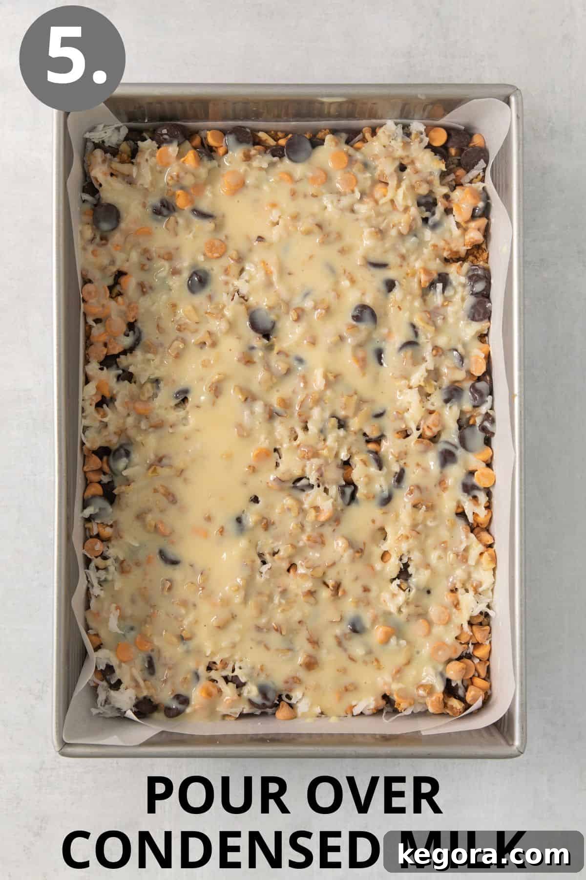 Gluten-Free Magic Bars 8 Sweetened condensed milk being poured generously and evenly over the top of the layered 7-layer bars, ensuring every component is coated.