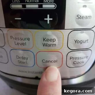 finger pressing the Cancel button on an Instant Pot to turn off the heating element