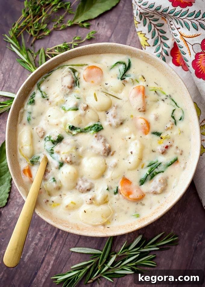 Creamy Sausage Gnocchi Soup in a beige bowl with a golden spoon
