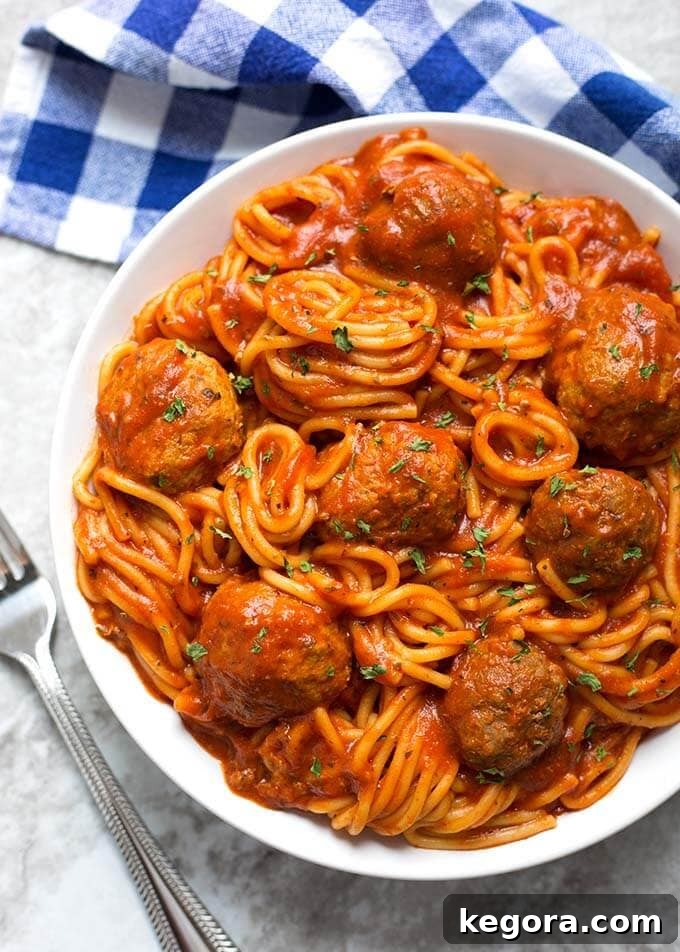 A delicious serving of Instant Pot Spaghetti and Meatballs on a white plate, garnished with fresh parsley.