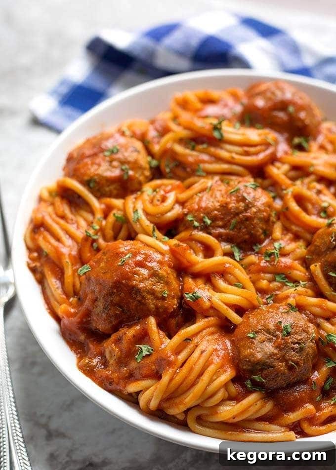 A close-up shot of Instant Pot Spaghetti and Meatballs on a white plate, showcasing the texture of the pasta and the rich sauce.