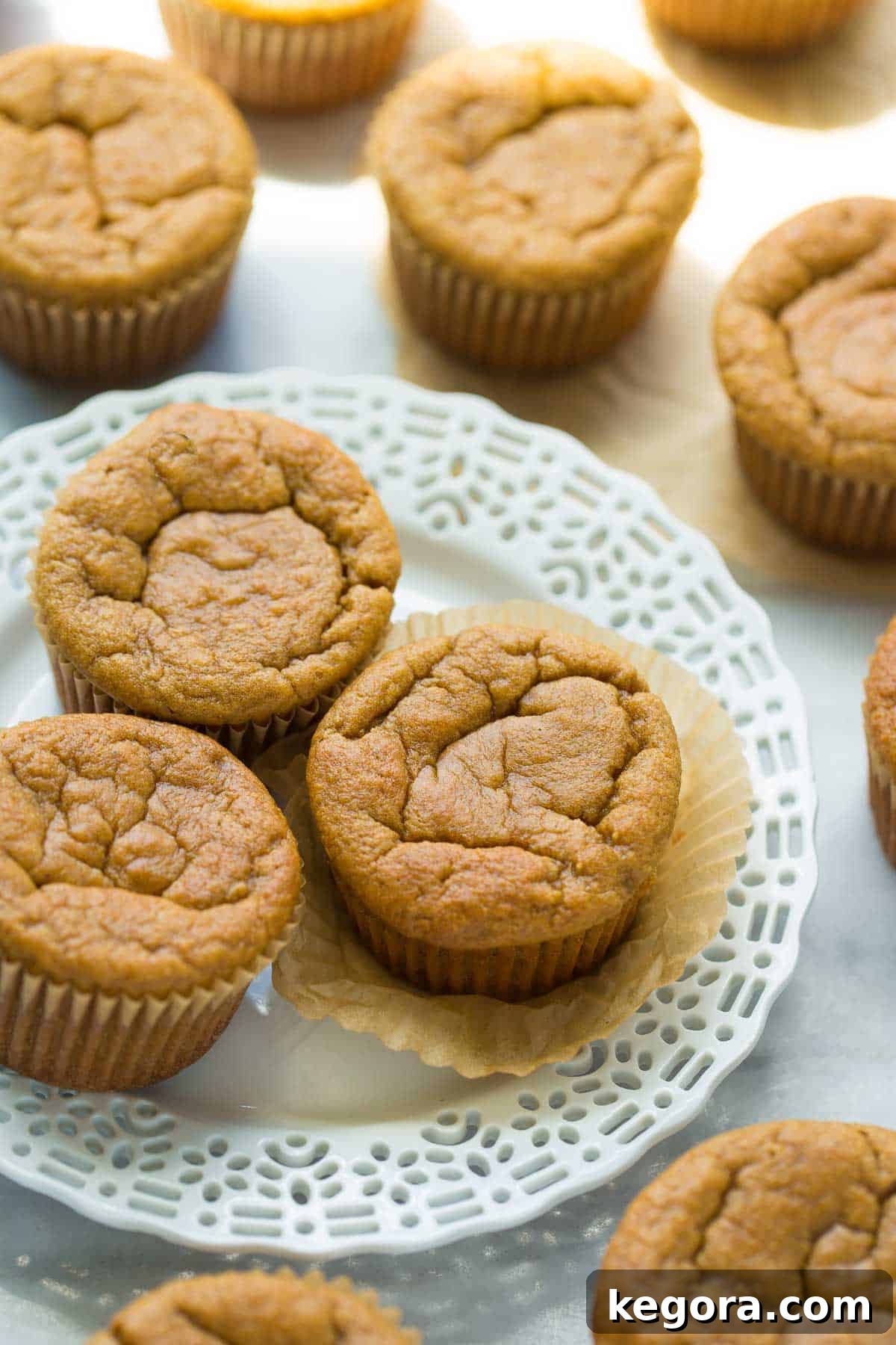 Tropical Banana Coconut Muffins 2 Golden brown coconut flour banana muffins arranged on a pristine white plate, set against an elegant marble background, showcasing their appealing texture.