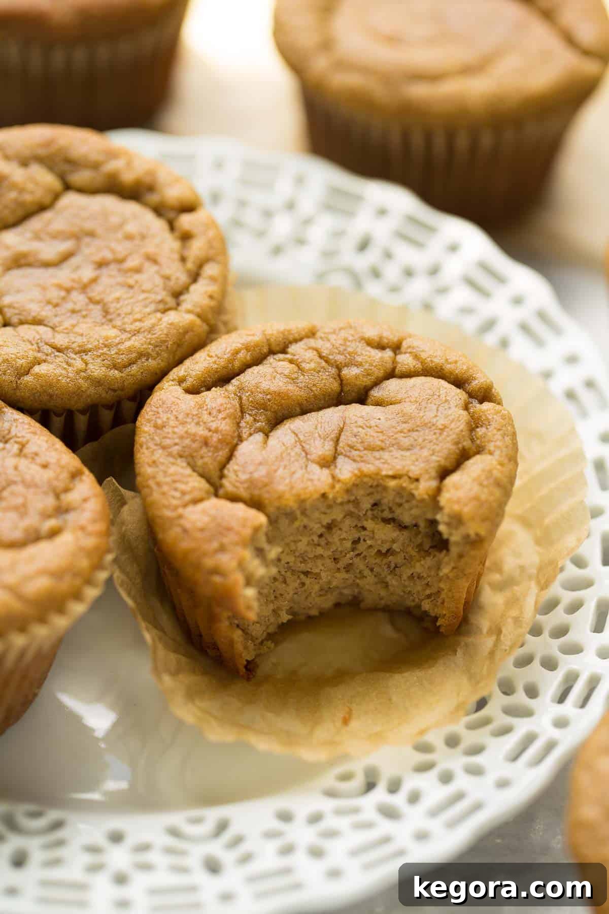 Tropical Banana Coconut Muffins 6 A close-up shot of a paleo banana muffin with a bite taken out, revealing its moist, tender interior and appealing texture, tempting to the viewer.