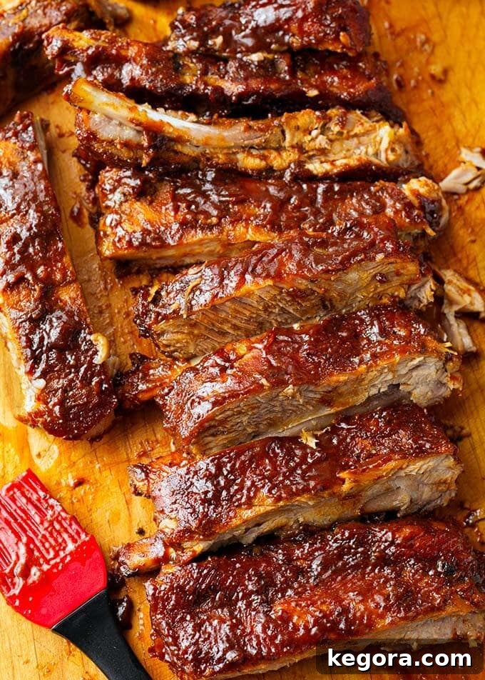 Sliced Slow Cooker BBQ Ribs on a wooden cutting board, garnished with fresh herbs