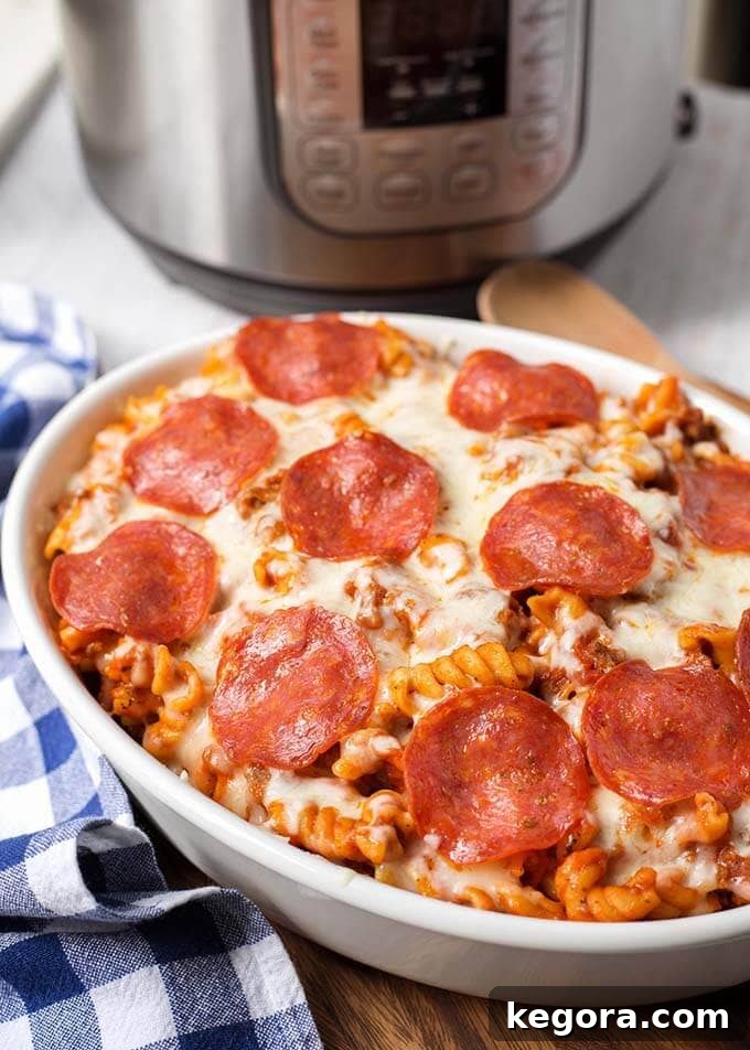 Instant Pot Cheesy Pizza Pasta Bake 6 White oblong baking dish of Pizza Pasta Casserole in front of a pressure cooker