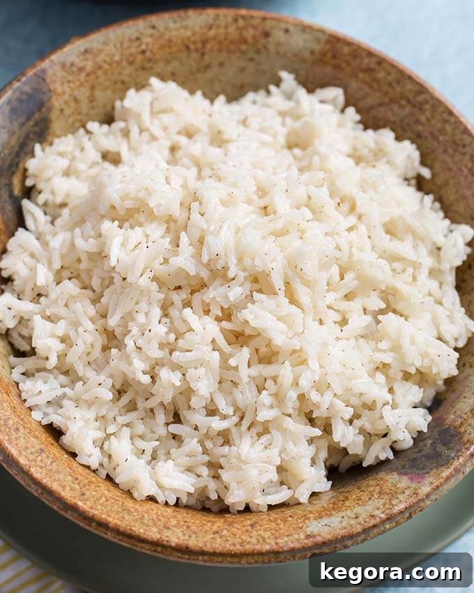 Foolproof Instant Pot White Rice 4 A close-up shot of perfectly cooked and fluffy white rice in a rustic brown stoneware bowl, ready to be served.