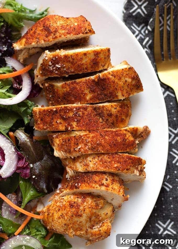 Mouthwatering Chicken Roast Blend 3 Perfectly sliced, seasoned baked chicken breast served on a pristine white plate, accompanied by a vibrant green salad, showcasing its tender and juicy interior.