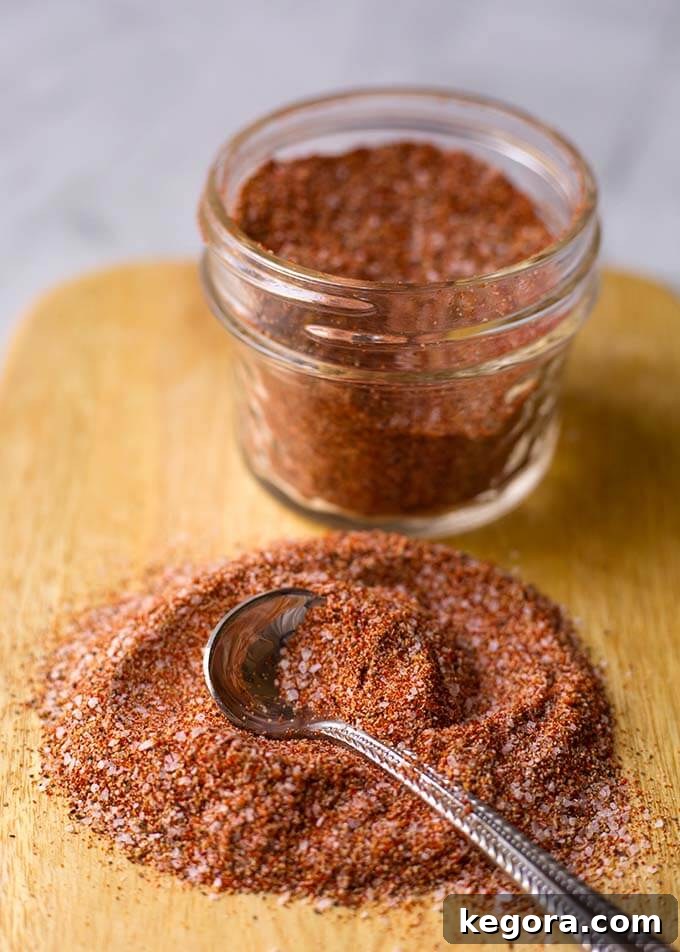 Mouthwatering Chicken Roast Blend 4 A close-up shot of a small mound of Baked Chicken Spice Rub on a wooden cutting board, with a tiny silver spoon, illustrating the texture and richness of the spice blend.
