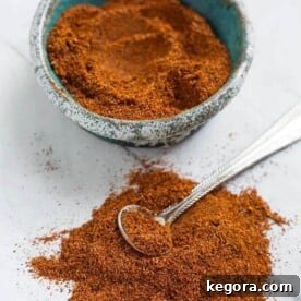 Homemade Fajita Seasoning in a turquoise stoneware bowl next to a pile of seasoning with a silver teaspoon