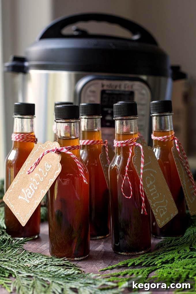 Several small bottles of Vanilla extract artfully arranged in front of a pressure cooker, ready for gifting.