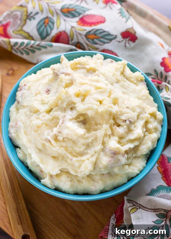 Creamy Mashed Potatoes in a blue bowl and a floral napkin all on a wooden board