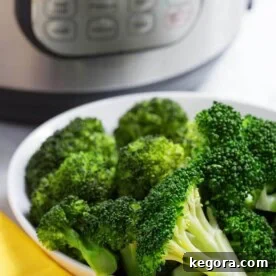 Cooked Broccoli in a white bowl in front of a pressure cooker