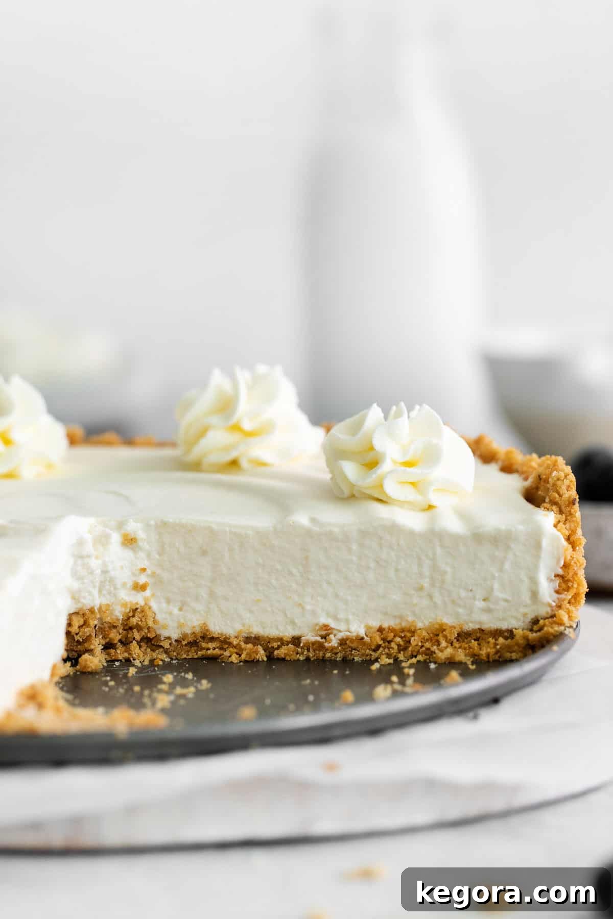 A whole gluten-free no-bake cheesecake in a serving dish with a single slice elegantly removed.
