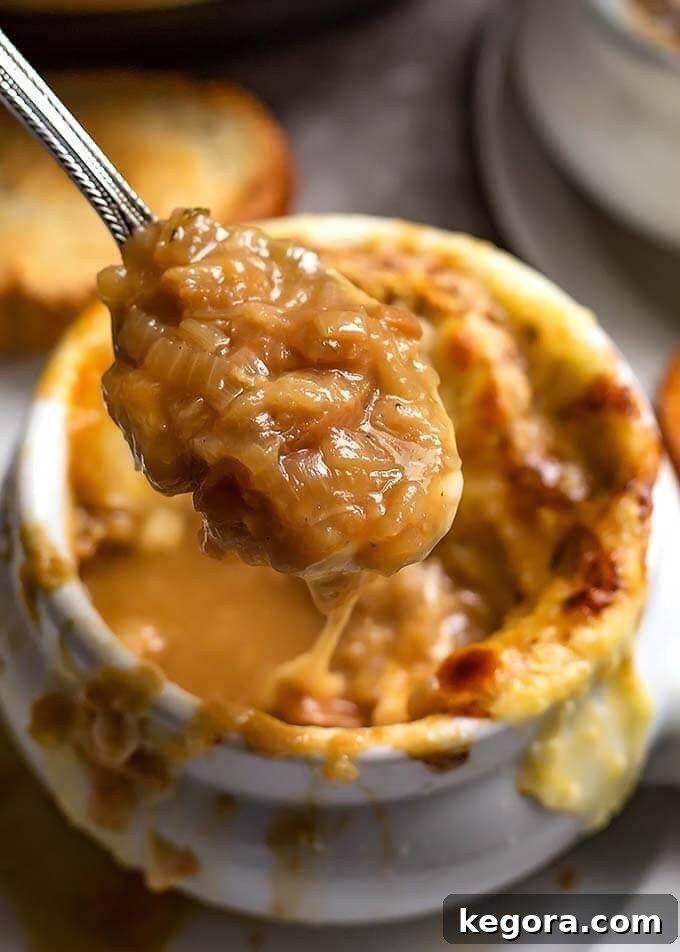 Close-up of a spoonful of Instant Pot French Onion Soup, showcasing the tender caramelized onions and rich broth, held above the bowl.