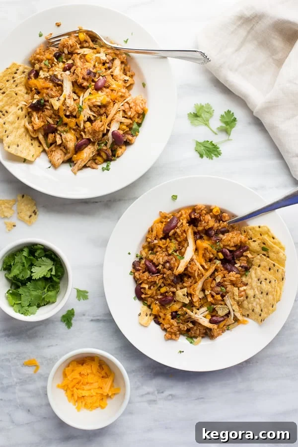 overhead shot of chicken and rice in white bowls with cilantro and cheese