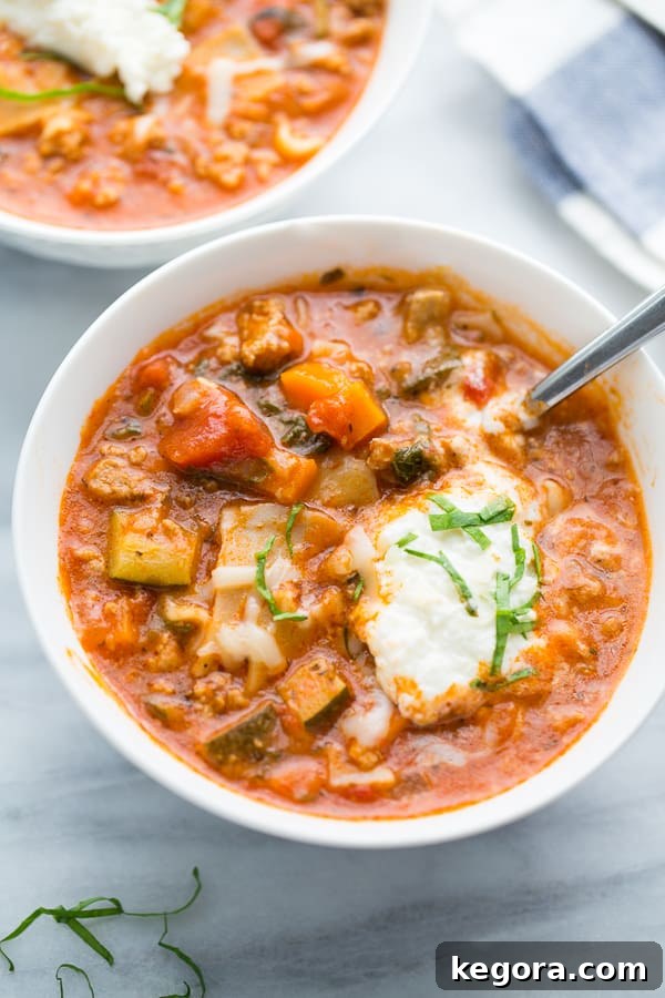 A close-up of Instant Pot Turkey Vegetable Lasagna Soup in a bowl, showcasing the rich texture, broken lasagna noodles, and colorful vegetables. A spoon is gently dipped into the soup, highlighting its appetizing depth.