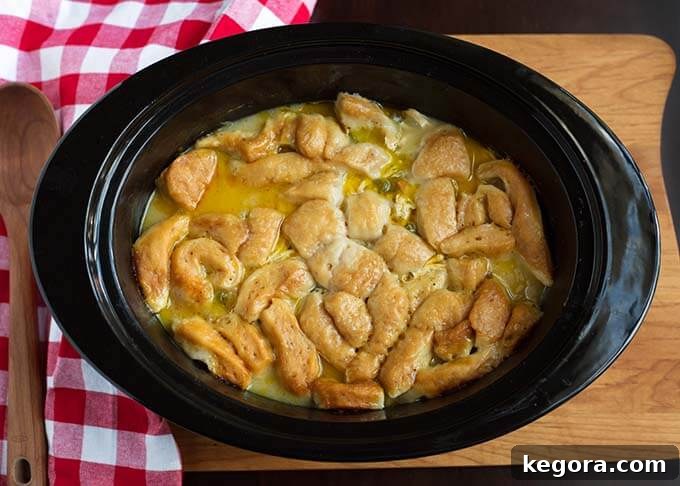 Easy Slow Cooker Chicken and Dumplings 4 Top view of Chicken and Dumplings in a slow cooker next to a red gingham napkin