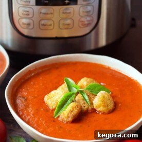 Fresh Tomato Basil Soup topped with croutons and fresh basil, in a white bowl