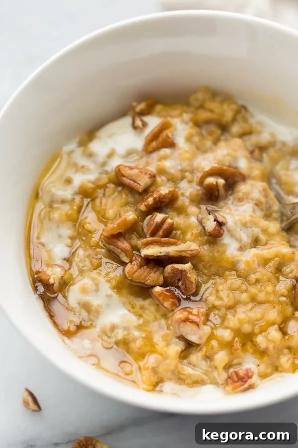 Instant Pot Pumpkin Maple Oatmeal A close-up shot of creamy pumpkin maple oatmeal in a white bowl, generously topped with crunchy pecans, highlighting its rich texture and delicious appeal.