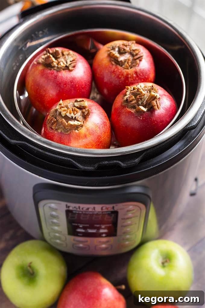 Four delectable baked apples simmering gently inside the Instant Pot pressure cooker