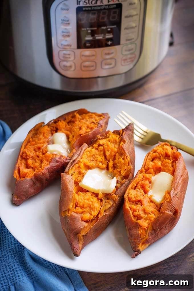 Three cooked sweet potatoes with butter and a gold fork on a white plate in front of a pressure cooker
