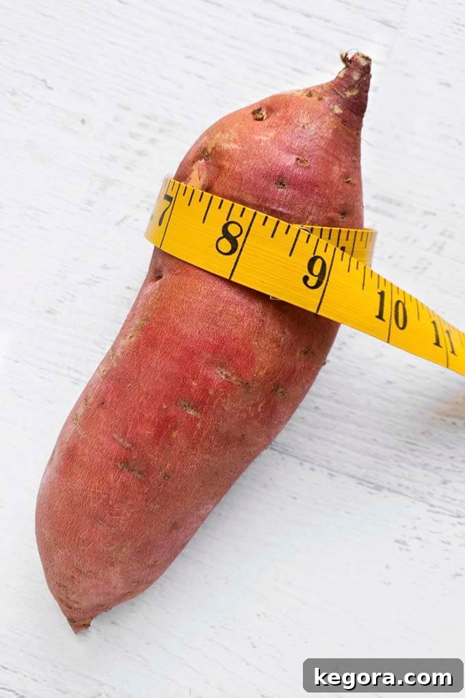Yellow measuring tape wrapped around a raw sweet potato to determine its circumference
