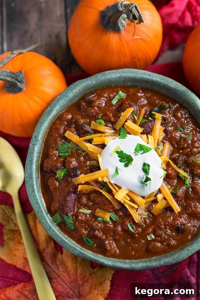 Pumpkin Chili topped with shredded cheese and sour cream in a turquoise bowl