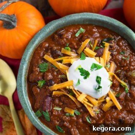 Pumpkin Chili topped with shredded cheese and sour cream in a turquoise bowl