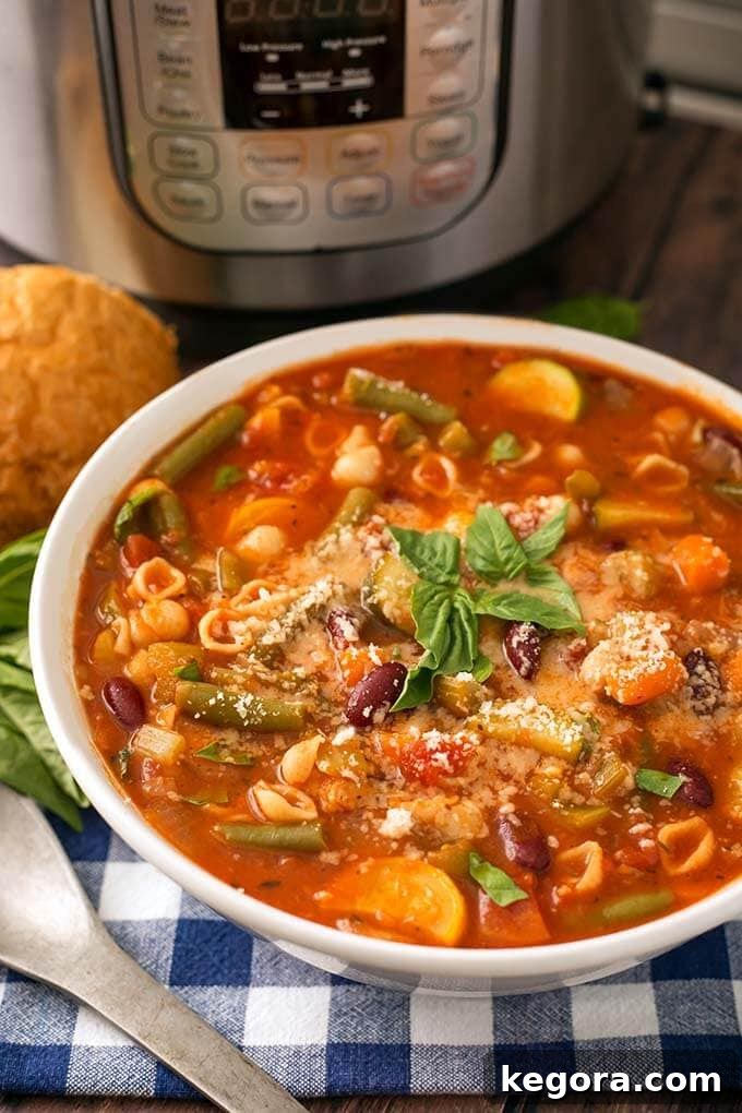 Effortless Instant Pot Minestrone Soup 2 Minestrone Soup in a white bowl in front of a pressure cooker, ready to be served