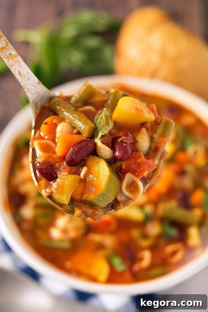 Effortless Instant Pot Minestrone Soup 3 Closeup of a spoonful of Instant Pot Minestrone Soup in a white bowl, showcasing vegetables and pasta