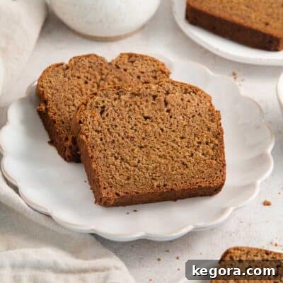 Two perfectly baked slices of gluten-free applesauce bread on a simple white plate.
