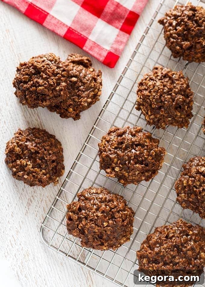 Several Chocolate Peanut Butter No Bake Cookies cooling on a wire rack next to a charming red gingham napkin, showcasing their rustic yet inviting appearance.