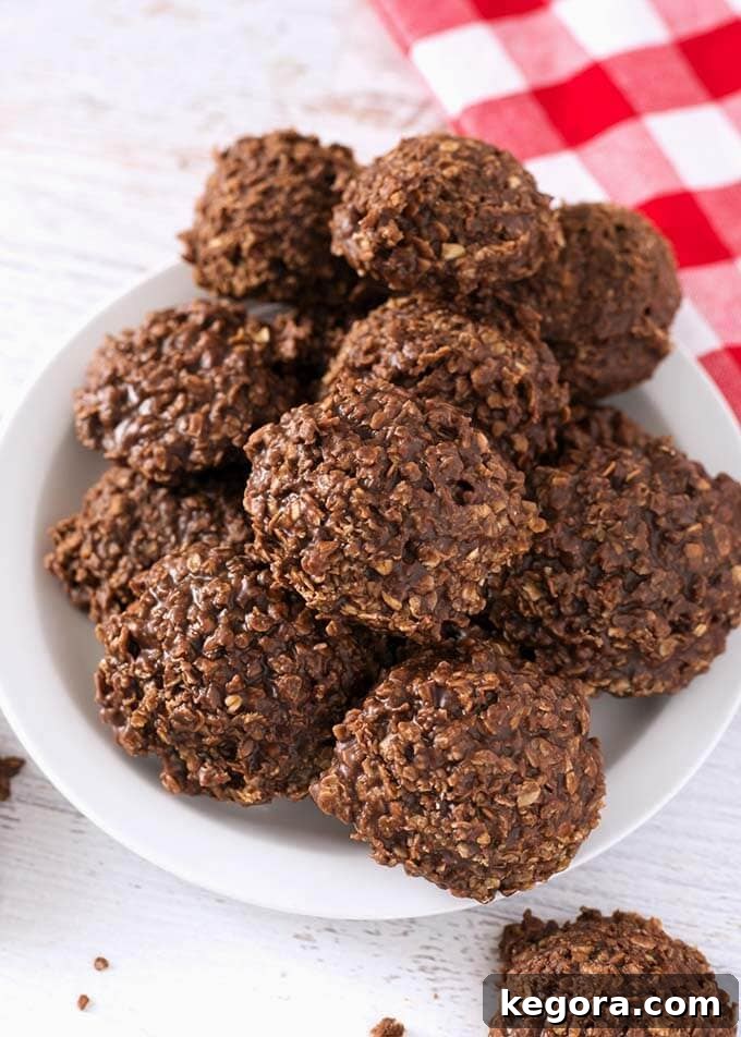 Speedy Chocolate Peanut Butter No-Bakes 3 A generous pile of homemade Chocolate Peanut Butter No Bake Cookies elegantly arranged on a white plate, accompanied by a festive red gingham napkin, inviting you to indulge.