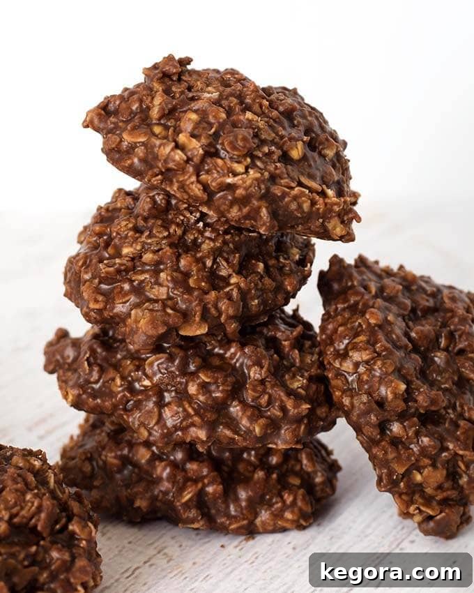 Speedy Chocolate Peanut Butter No-Bakes 4 A delicious stack of four Chocolate Peanut Butter No Bake Cookies, with more cookies visible in the background, highlighting their tempting texture and inviting appeal.