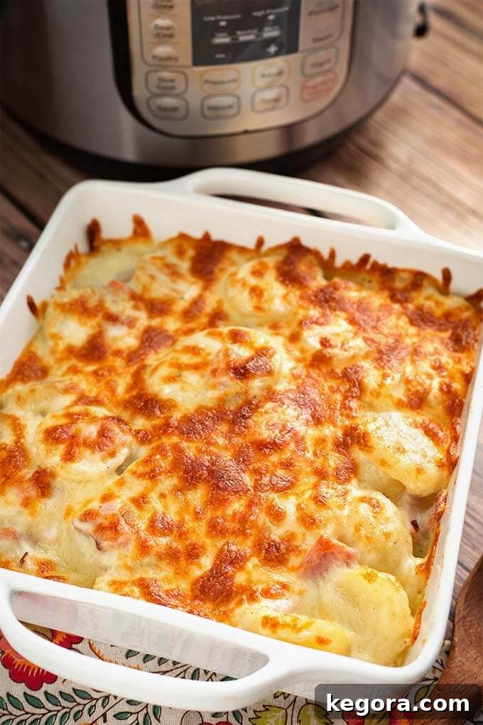 Cheesy Instant Pot Scalloped Potatoes with ham in a white square baking dish, ready to serve, next to an Instant Pot