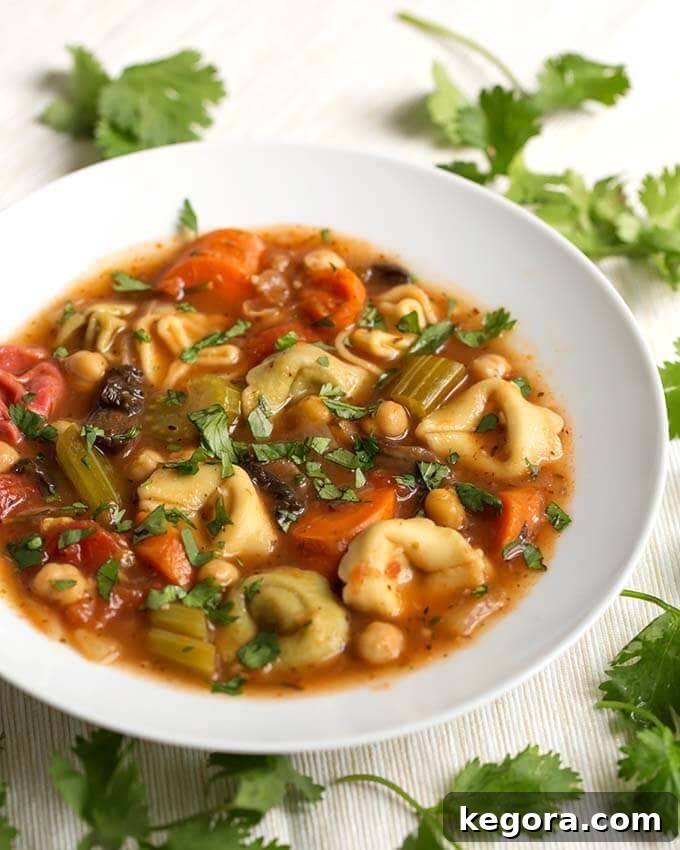Vegetable Tortellini Soup in a white bowl next to fresh parsley