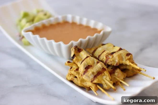 Delicious Chicken Satay skewers artfully arranged with a bowl of homemade Peanut Dipping Sauce