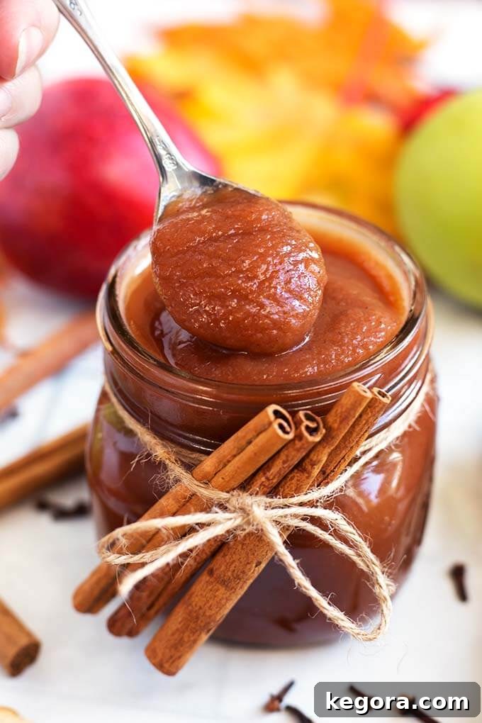 Quick Homemade Instant Pot Apple Butter 7 Closeup of a spoonful of Apple Butter from a Small glass jar of Apple Butter with cinnamon sticks tied with twine
