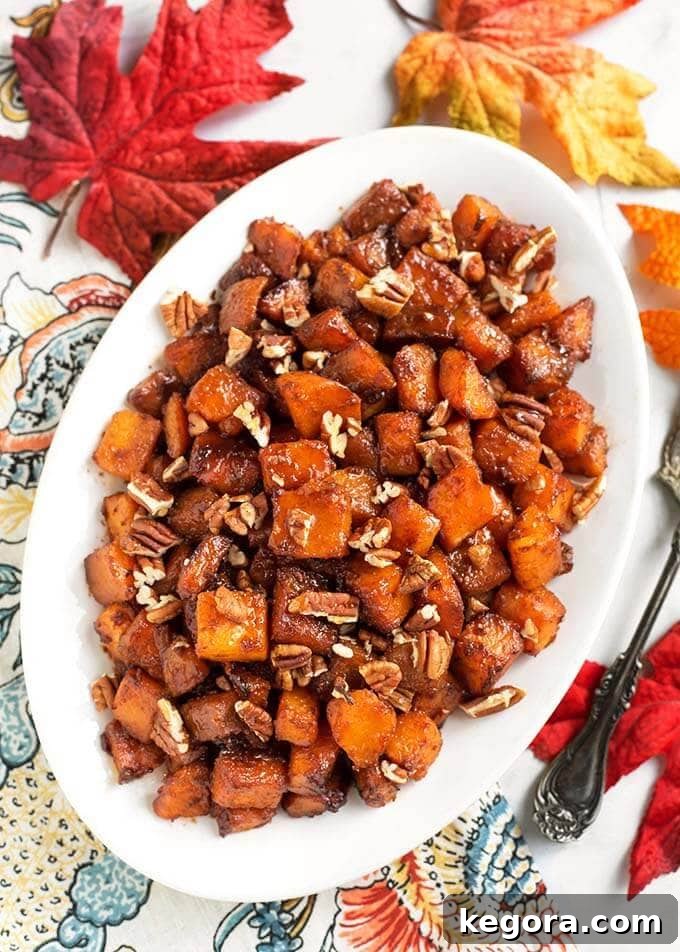 Maple Cinnamon Butternut Bliss 3 Top-down view of Cinnamon Roasted Butternut Squash on a white oblong platter, resting on a charming floral napkin, emphasizing its inviting texture