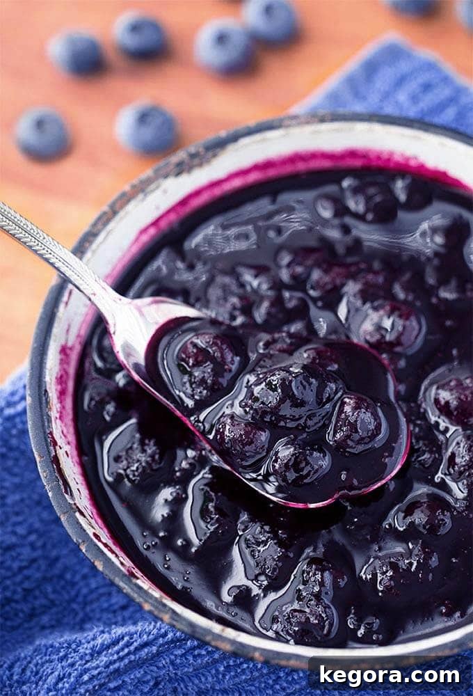 Luscious Blueberry Compote 2 Blueberry Compote in small bowl with silver spoon, a sweet and delicious topping for various dishes.
