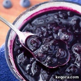 Luscious Blueberry Compote 5 Blueberry Compote being spooned out of small bowl with silver spoon